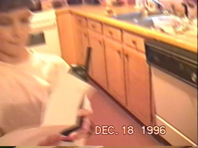 Vintage 1996 home video of floodwaters surrounding a house as a young boy reads a note in the kitchen
