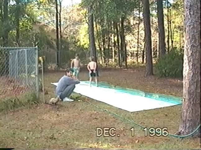 A vintage 1996 home movie shows young boys and a dog taking turns on a backyard slip 'n slide as their father watches