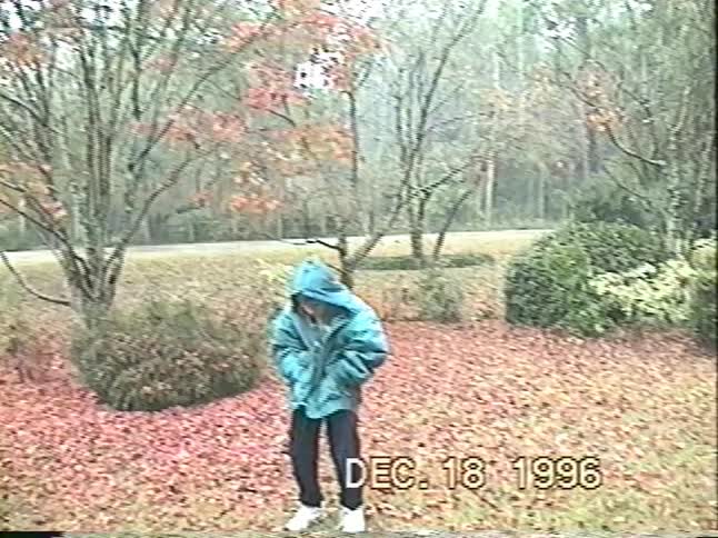 Vintage VHS footage from 1996 shows a happy child in a puffy coat enjoying the first sleet of winter in their backyard