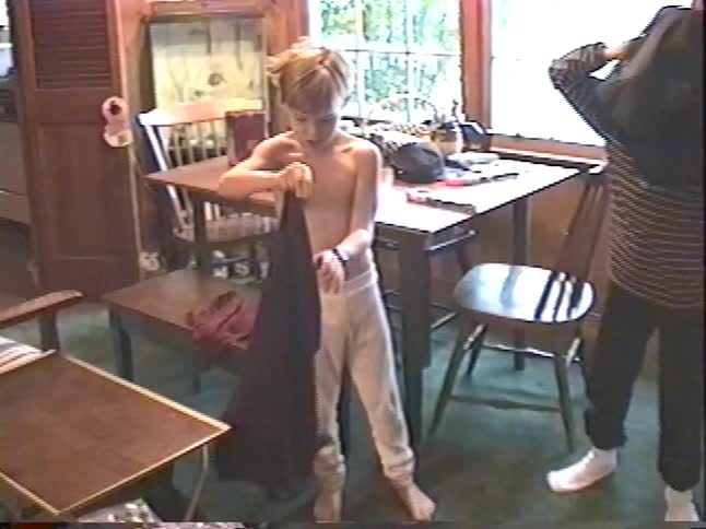 Vintage VHS footage shows two young brothers excitedly opening and trying on new baseball jerseys and caps on Christmas morning