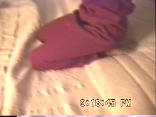 Warm home video of a woman and young child sitting in bed watching television in a softly lit bedroom