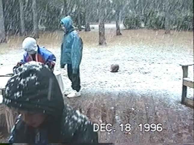 Vintage VHS home video from 1996 shows children excitedly playing outside on their backyard deck during a heavy snowstorm