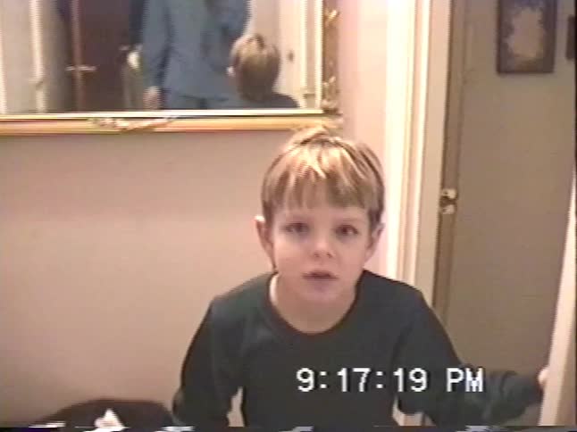 A young boy proudly shows off his colorful Cat's Cradle string creation in a charming home video from the 1990s