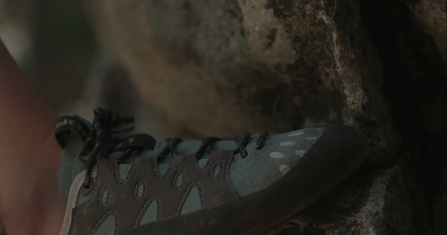 A foot is placed in a dip between rocks