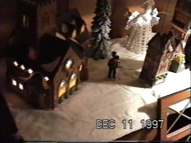 A vintage home video from 1997 slowly reveals a miniature Christmas village with lighted buildings and figurines
