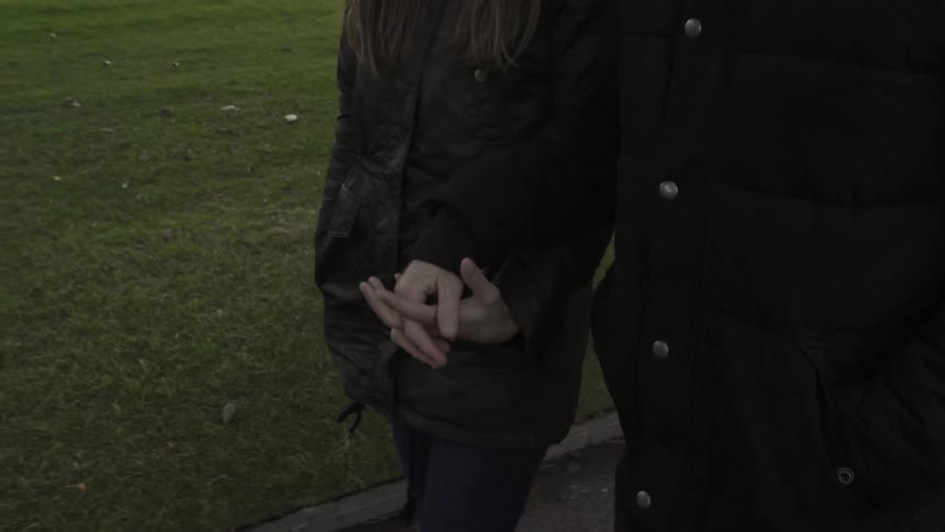 A man and woman clasp hands as they are walking