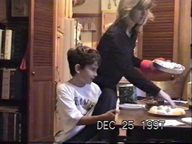 A nostalgic home video from Christmas Day 1997 shows a mother serving a meal while her son waits at the kitchen table