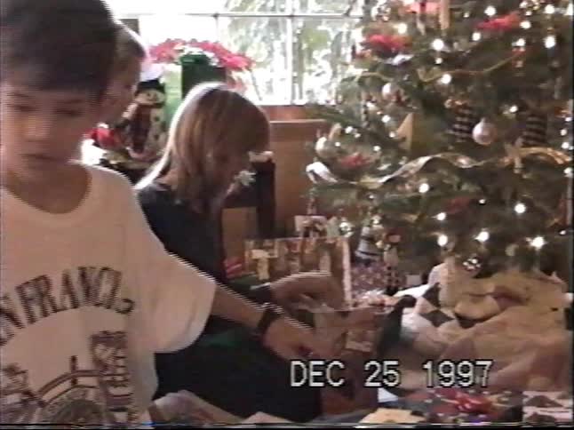 A mother and her two sons open presents by the Christmas tree on a nostalgic Christmas morning in 1997