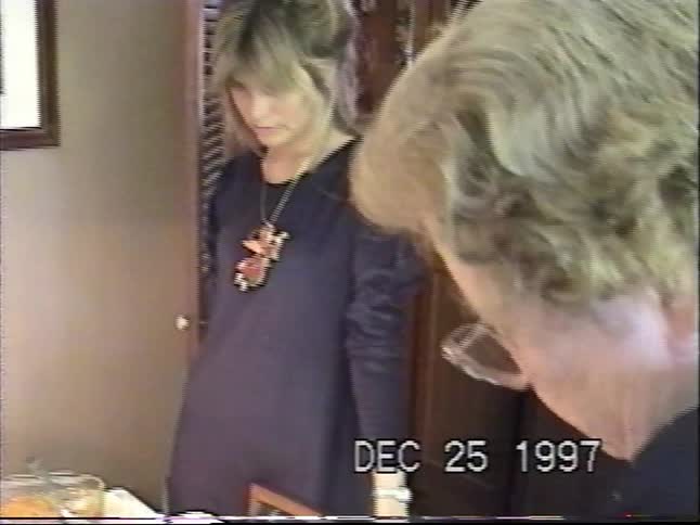 A family gathers for a festive Christmas dinner around a table laden with food in this vintage home video from 1997