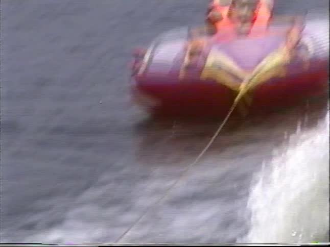 Vintage footage captures a young girl in a life vest having a blast while tubing on a lake