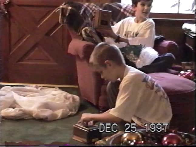 Two young brothers open their presents together on Christmas morning in 1997