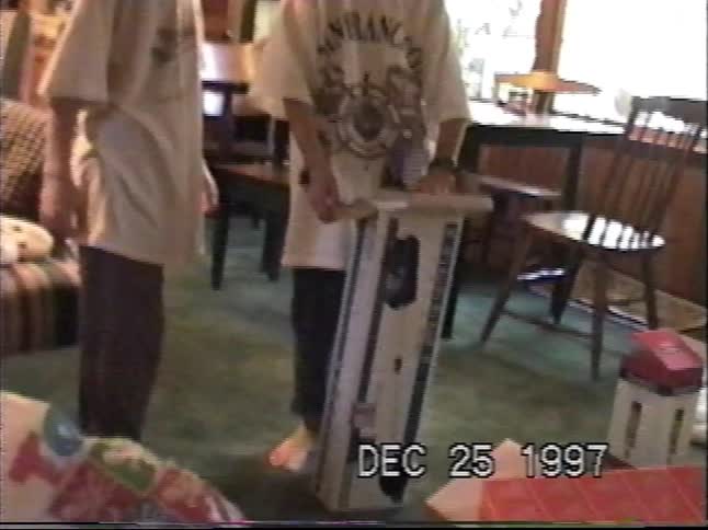 A family with three children excitedly opens presents in their living room on Christmas morning in 1997