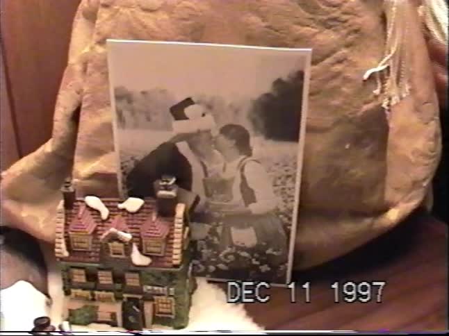 A slow pan and zoom on a vintage miniature Christmas village display with lighted houses and figurines, shot on home video in 1997