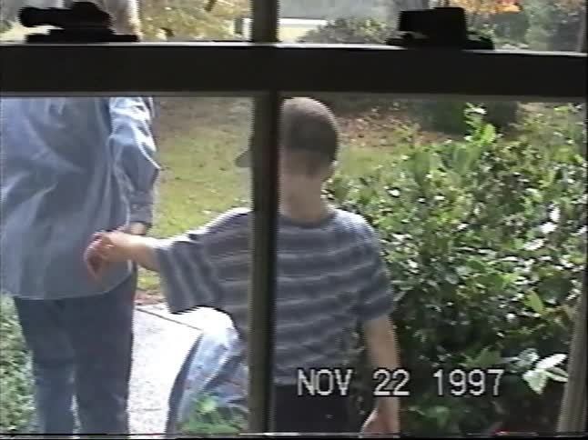 Vintage VHS home movie from 1997 shows a mother and her two young sons walking in the yard as seen from a window
