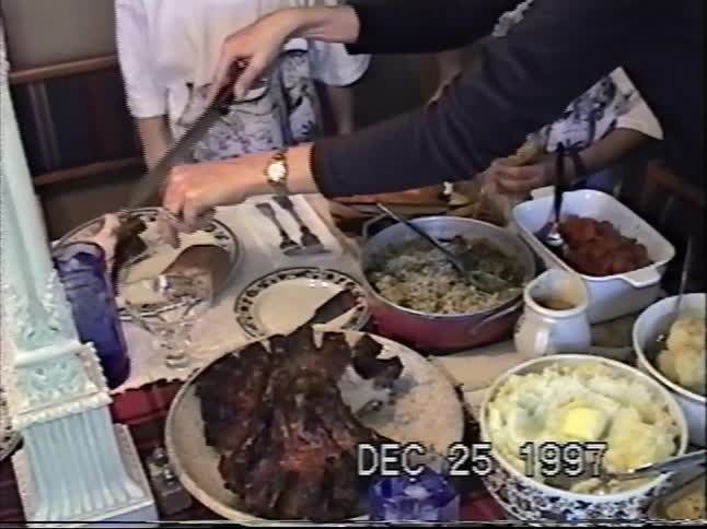 Vintage VHS footage from Christmas 1997 shows a family carving a roast and serving a festive holiday dinner