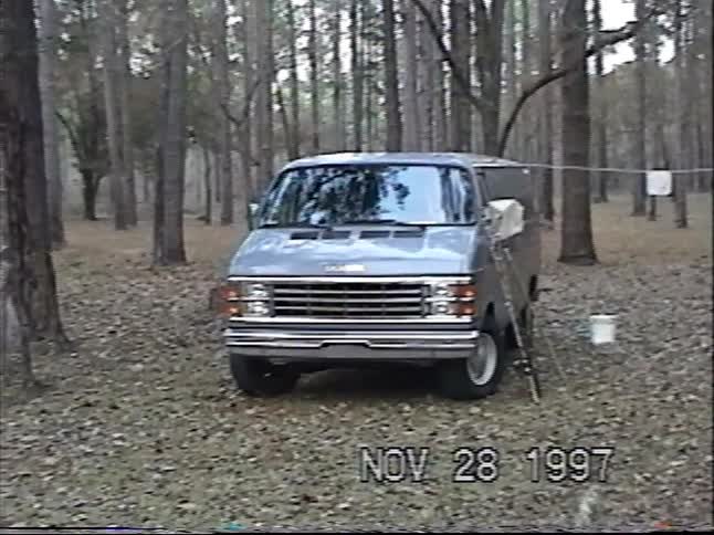 A pan across a family campsite in the woods reveals tents, picnic tables, and a boy in 90s attire, captured on VHS tape