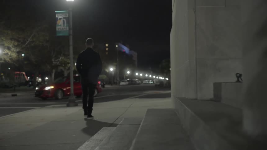 Man walks down a sidewalk at night