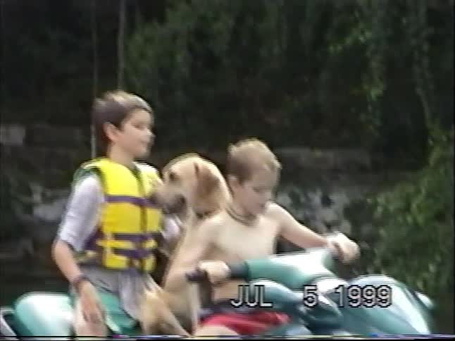 Two young boys and their dog pose for a picture on a jet ski before riding off on a lake in the summer of 1999