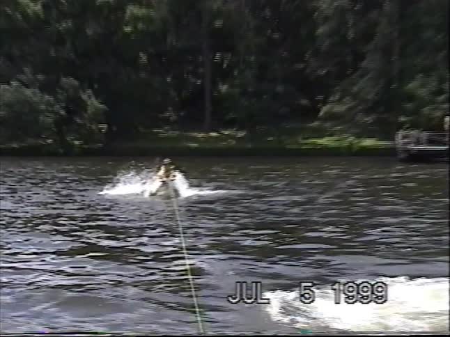 A water skier gets pulled up by a boat on a lake and then crashes into the water in a nostalgic home video from 1999