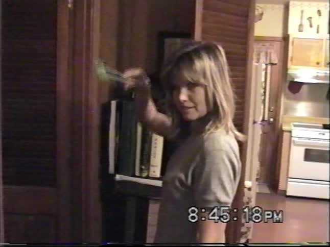 A young woman playfully poses with a fly swatter before putting it away in a wooden closet at home