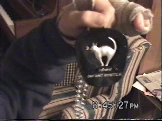 Vintage home video of a child indoors showing a black pendant necklace close to the camera in a cozy living room