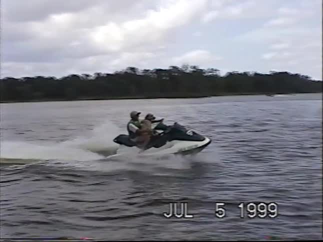 Vintage home movie footage from 1999 captures a man and his happy dog riding a jet ski in slow motion on a lake