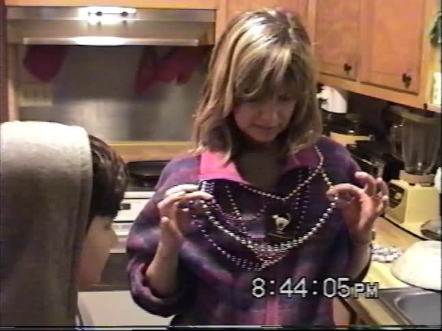 A mother and her two sons wash and admire a collection of Mardi Gras beads in their kitchen in this 1999 home video