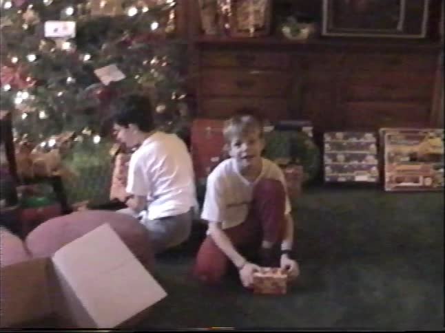 A vintage home video shows two young brothers opening presents by the Christmas tree on Christmas morning in 1999