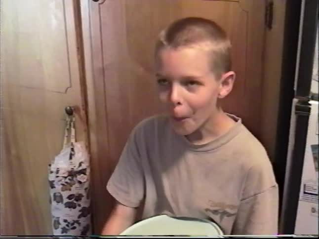 Boy takes a plate from the refrigerator and carries it through a cozy home kitchen