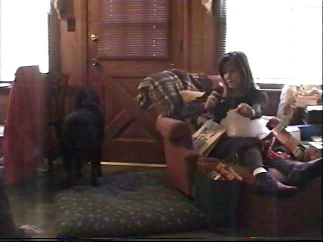 Vintage footage captures the joy of a young boy receiving a gift as his family and dog watch during a celebration
