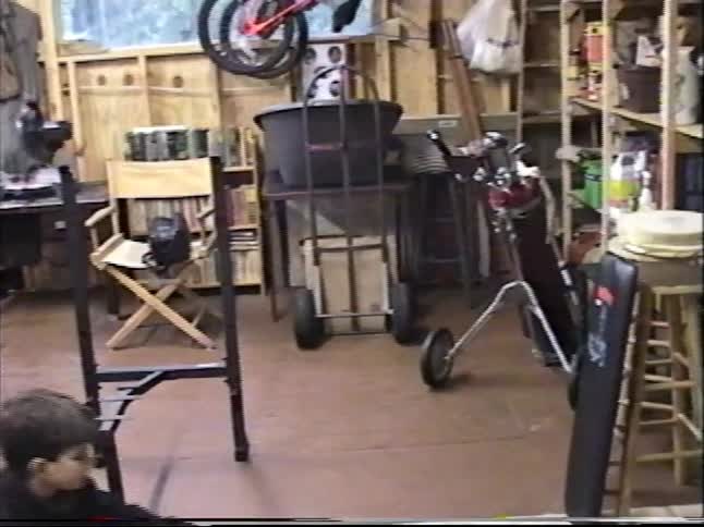 Vintage VHS footage shows a father and son working together to assemble new exercise equipment in their home workshop