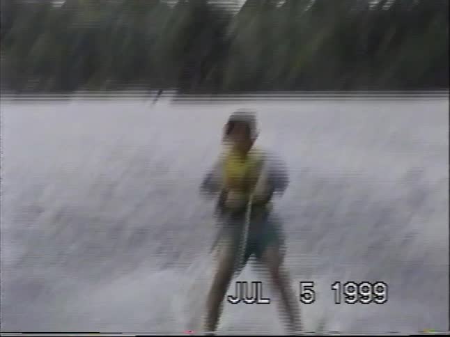 A boy water skis behind a boat on a lake on a summer day in this home video from 1999