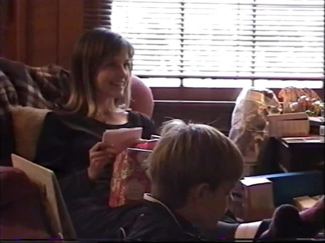 Nostalgic VHS home movie of a family with children opening gifts around the Christmas tree on Christmas morning