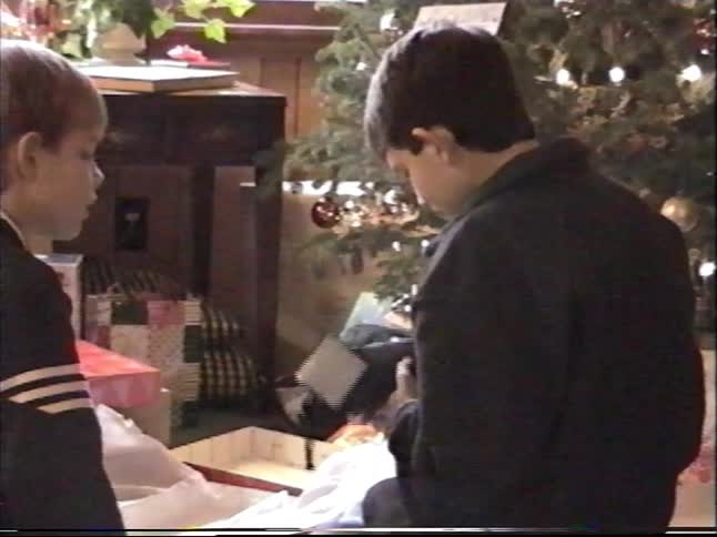 A nostalgic home video shows a young boy happily unwrapping a new pair of Adidas shoes on Christmas morning as his brother watches