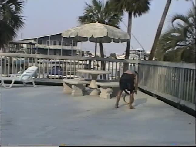 Vintage home video of young boys splashing, jumping, and playing in a sunny resort swimming pool