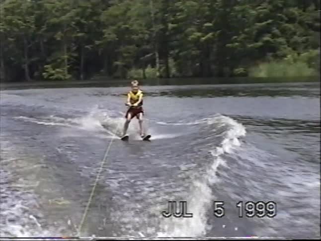 A young boy successfully water skis on a lake before taking a big splash in this authentic 1999 home movie
