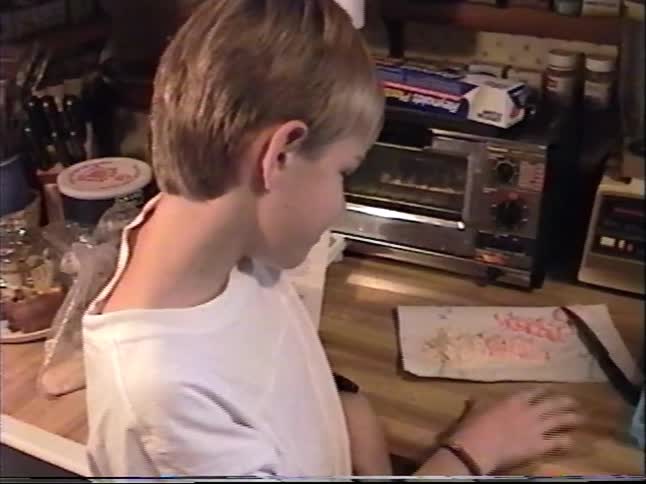 Vintage home video of children preparing food together on a kitchen counter