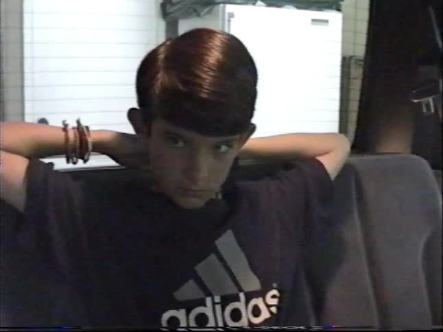Vintage VHS footage shows a young boy with a 90s haircut talking and relaxing in the backseat of a minivan