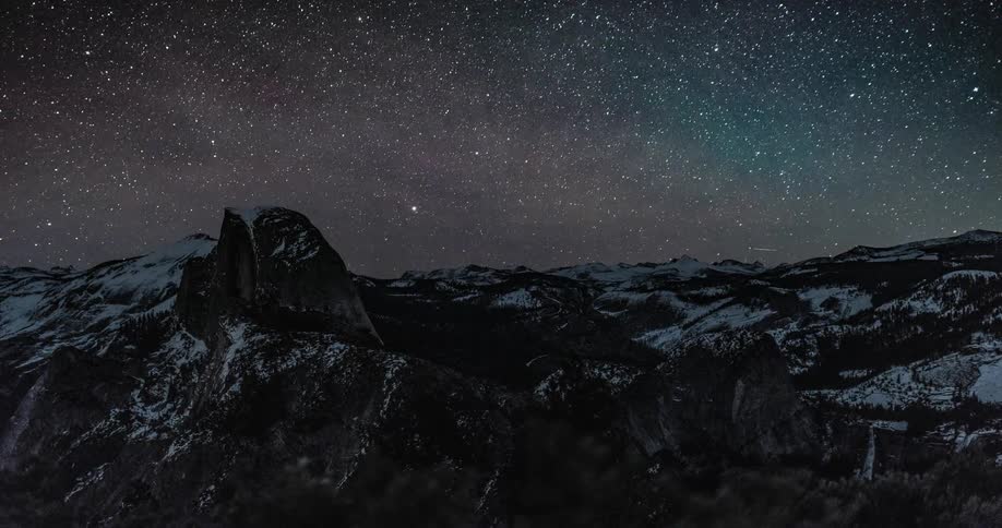 The stars travel across the sky over a snowy mountain