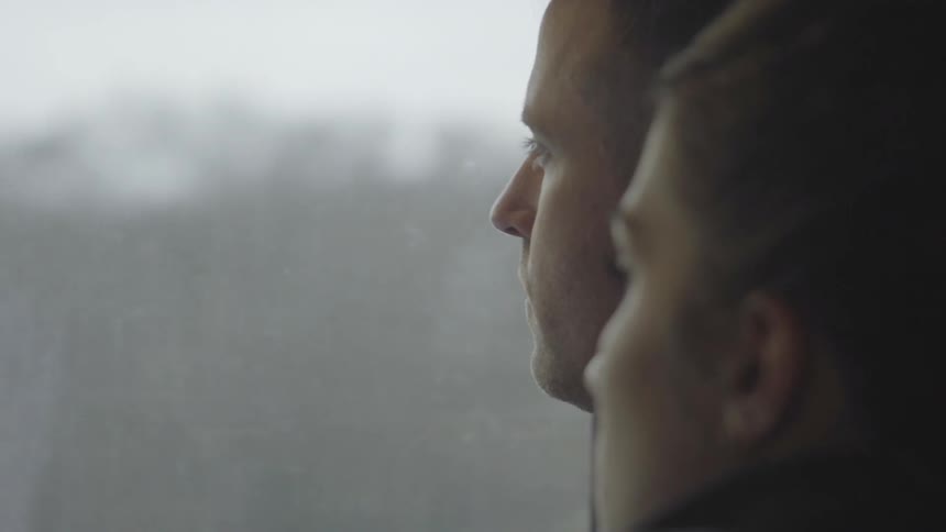 Man and woman sit in a vehicle looking out the window