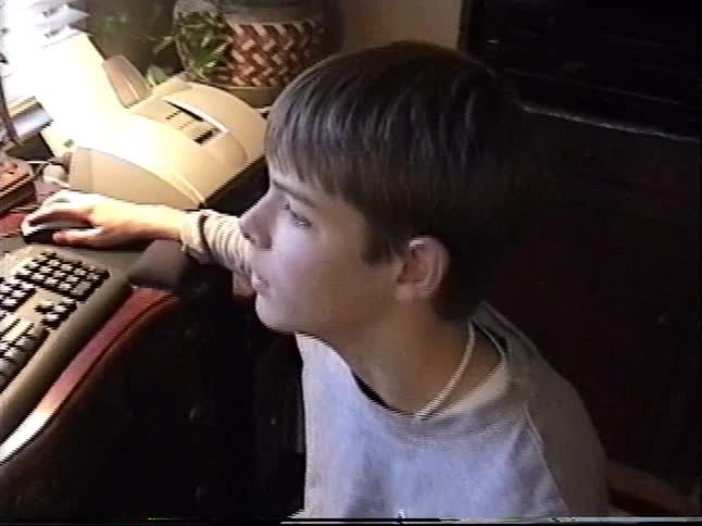 Vintage VHS footage from the 2000s shows a young boy sitting at a desk using an old desktop computer