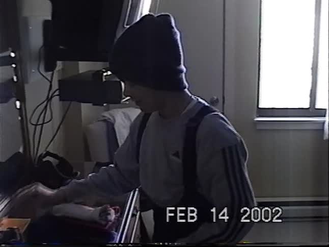 A young boy in winter clothes gets ready in a hotel room and smiles as he shows a dollar bill to the camera