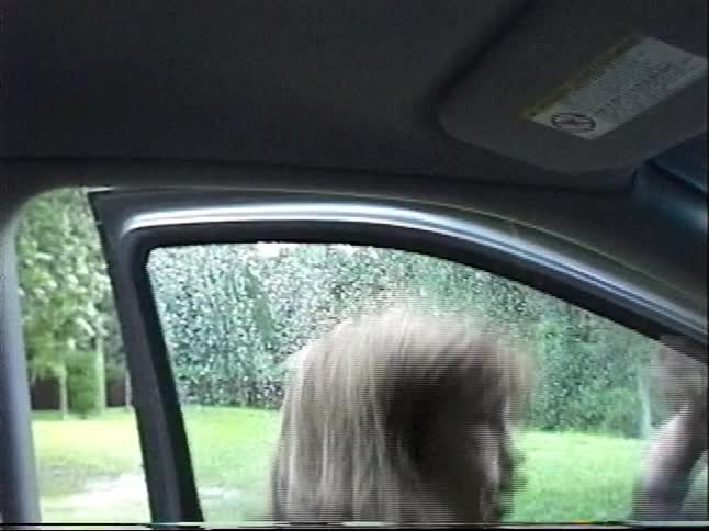 Vintage home video shows a family getting into their car to drive through a flooded, wooded area after a storm
