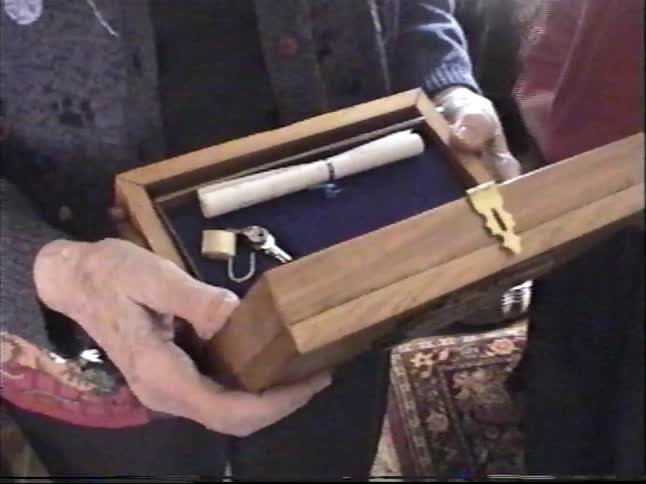 Vintage footage of a woman opening a wooden keepsake box containing a scroll and a lock and key during Christmas
