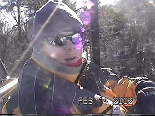 Vintage home video from 2002 shows a young boy in winter clothes riding a chairlift at a ski resort