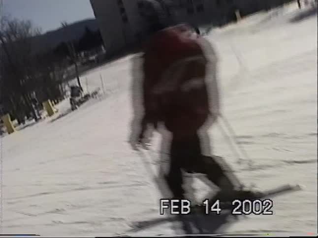 Point-of-view footage from 2002 follows a skier in a red jacket down a sunny, snow-covered mountain slope