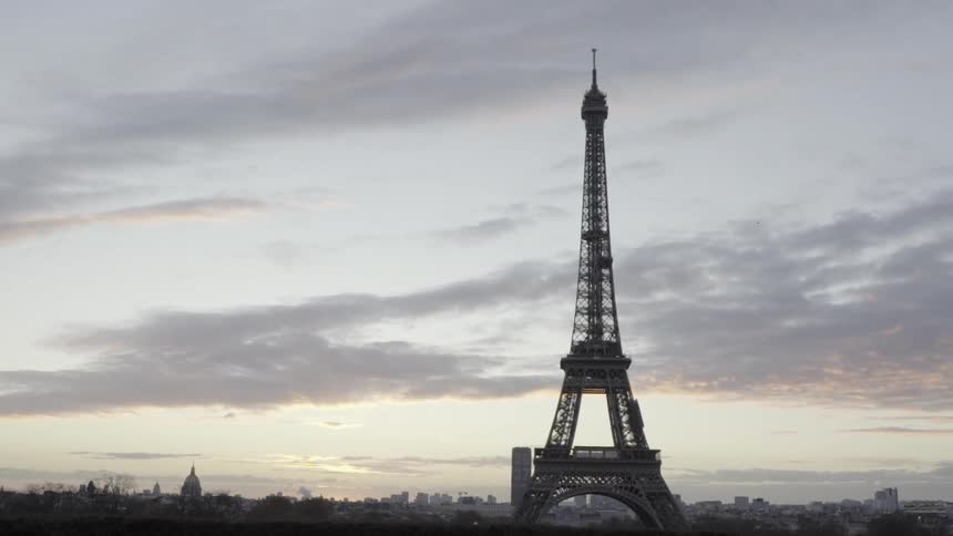 The eiffel tower sits under a cloudy sky at dawn