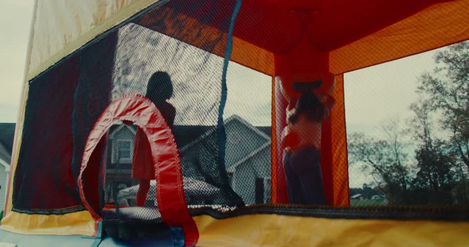 Slow motion shot of several children jumping and playing inside a large inflatable bounce house