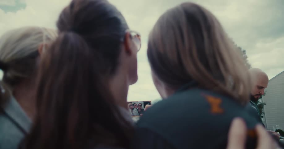 Over-the-shoulder view of friends taking a group selfie on a mobile phone