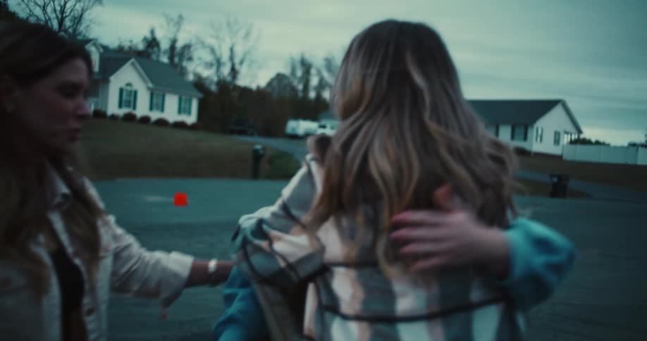 Three happy female friends have an emotional reunion, running to embrace each other in a warm hug on a suburban driveway at dusk